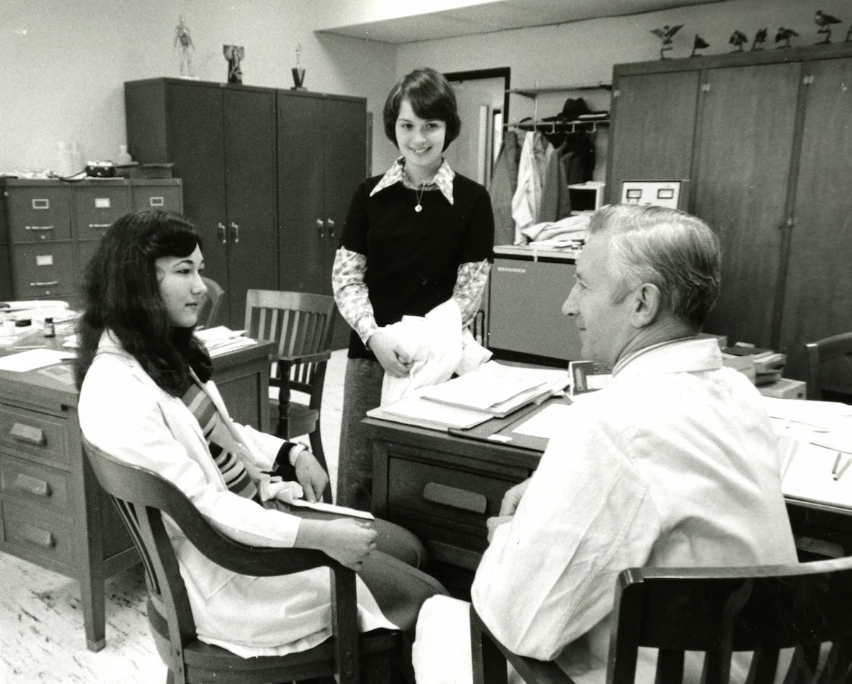 students and teacher sitting at desk