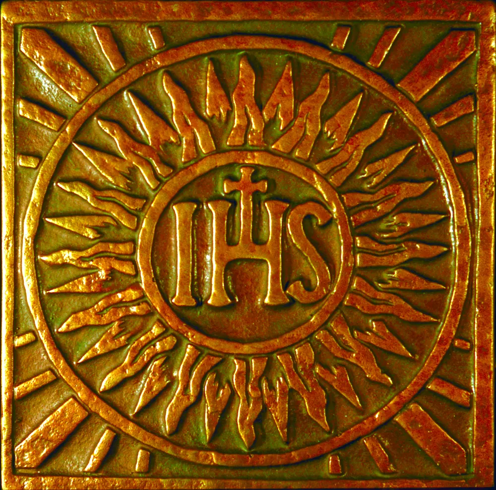 stone wall with sun and  letters IHS inscribed