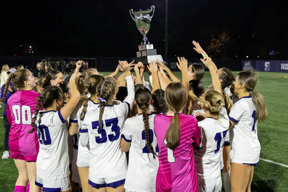 women's soccer team holds up championship trophy